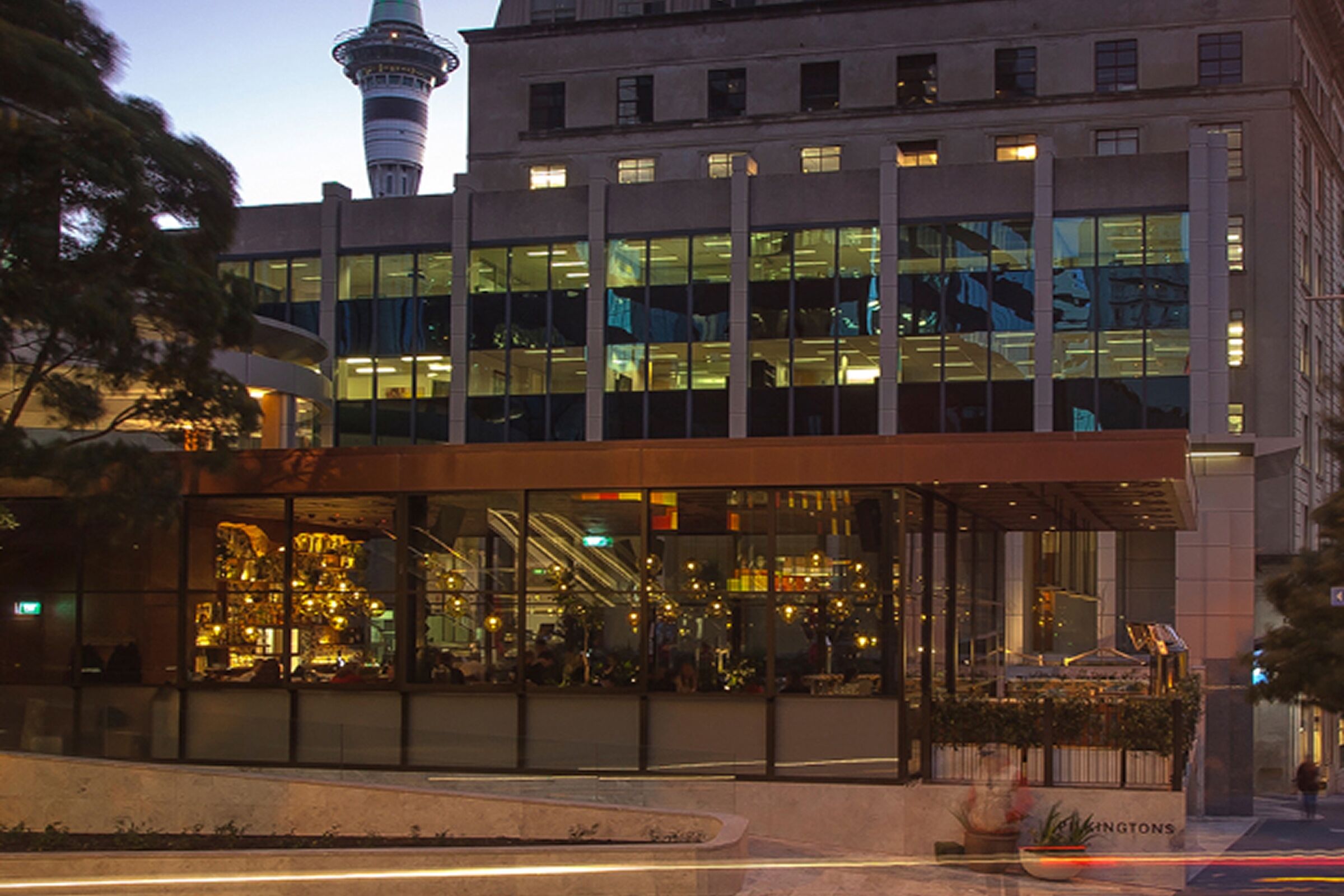 Pilkingtons: heritage buildings above the new glass pavilion at dusk, Sky Tower behind
