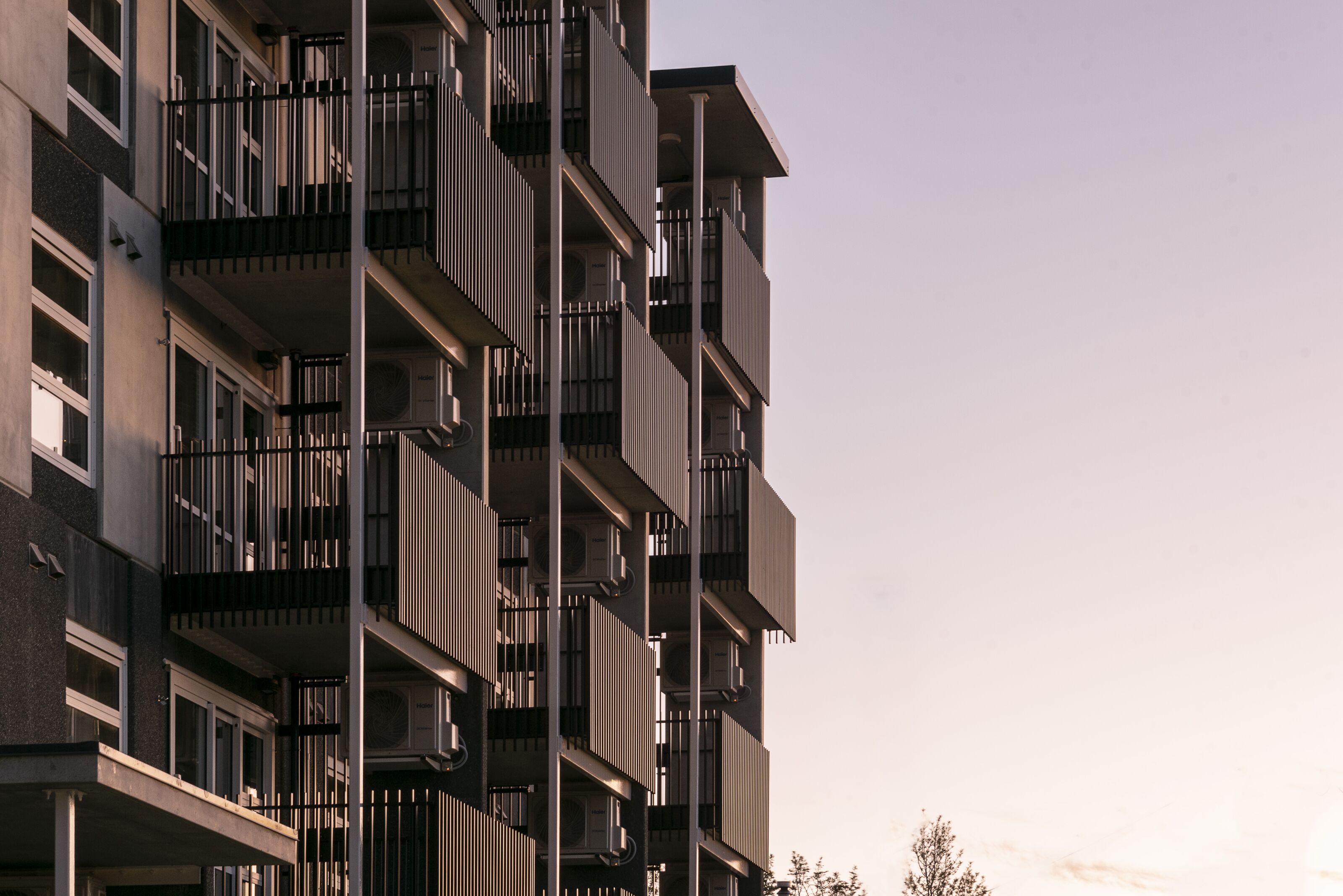 Apartment building facade with stacked balconies and timber screening at dusk