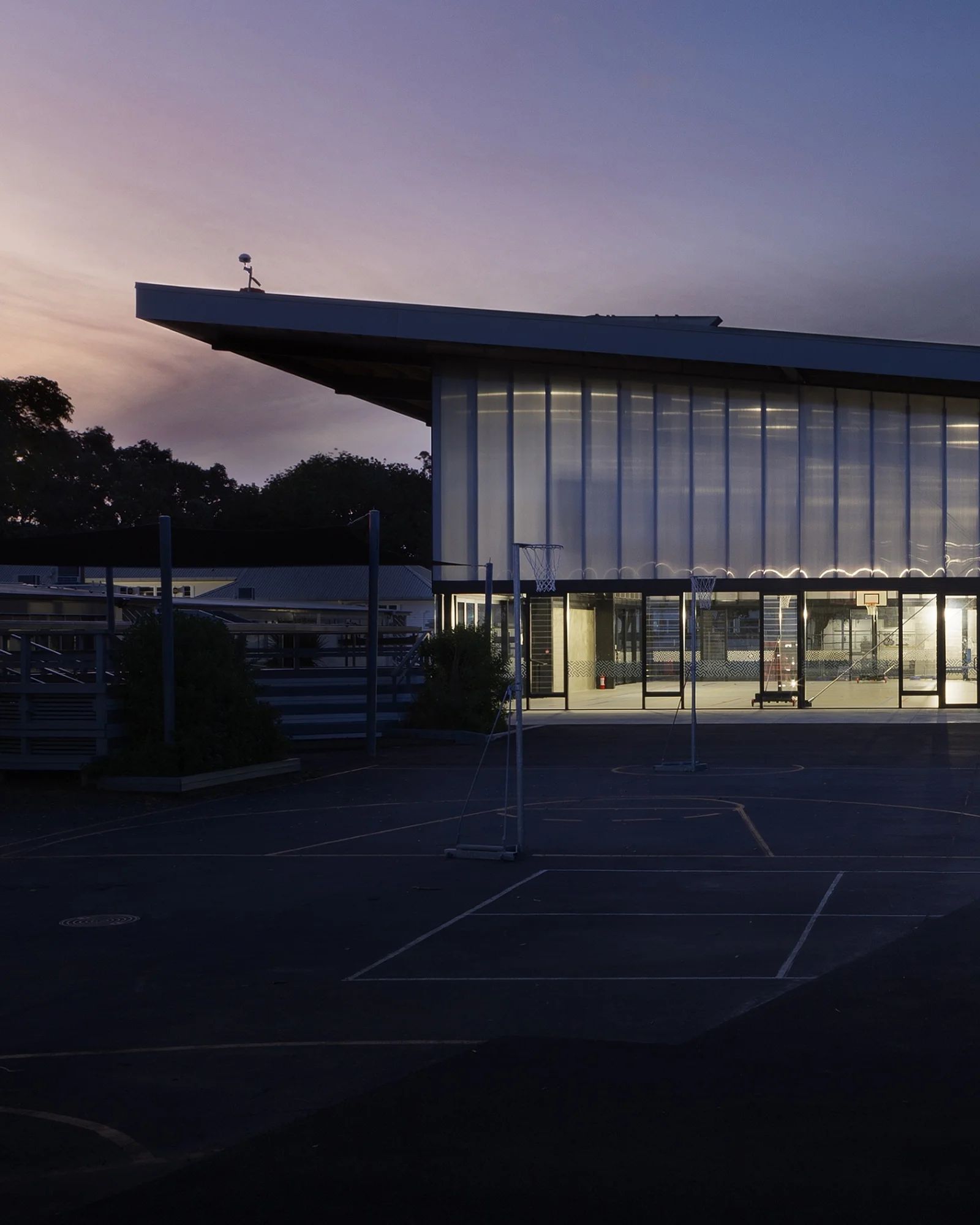 A two-storey glazed education building lit from within at dusk