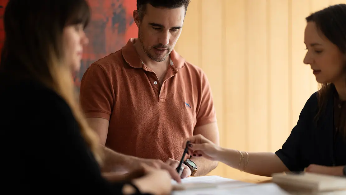 Ministry designers examining a material sample together at a studio table