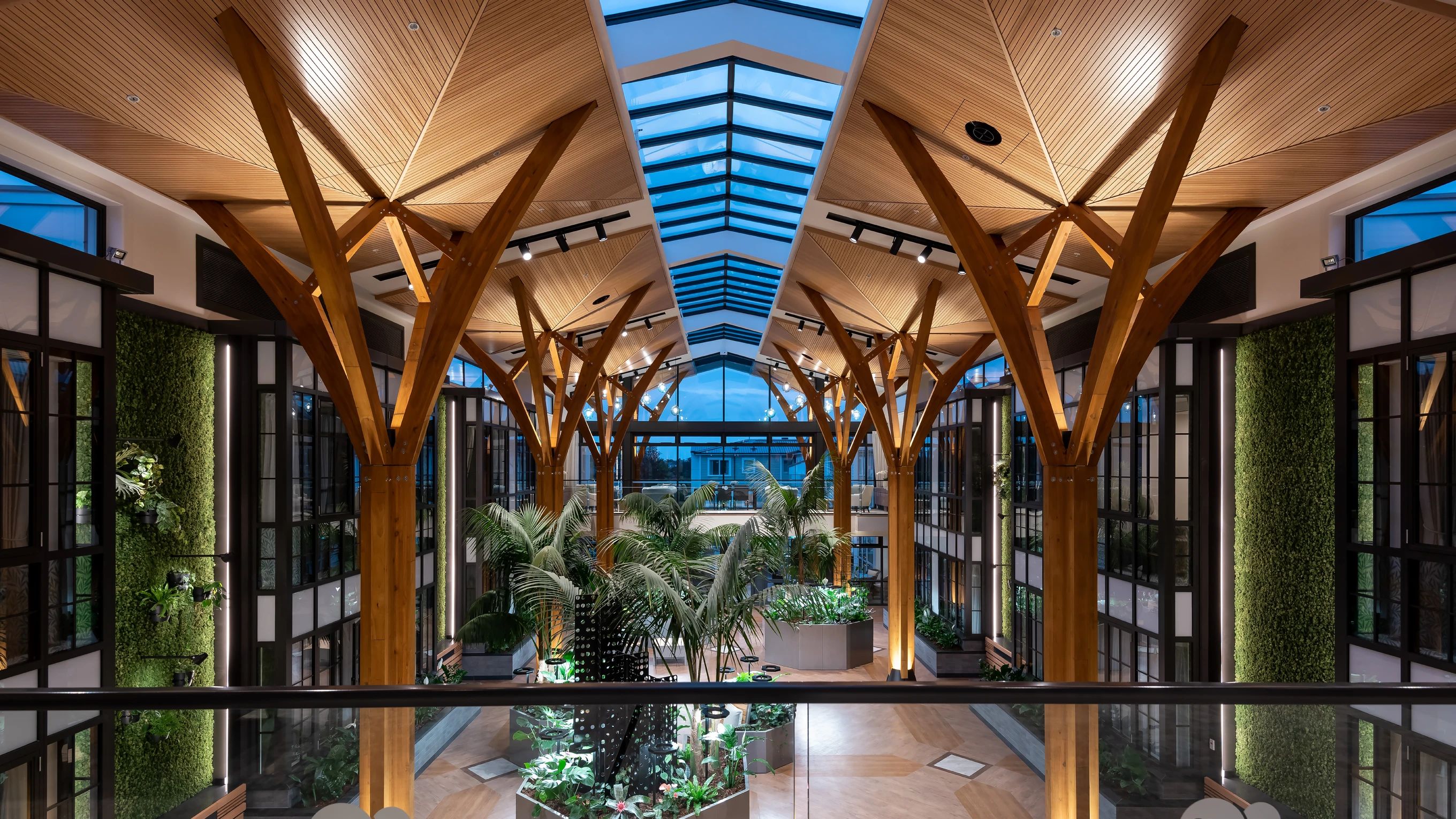 Rawhiti Estate atrium with branching timber columns, a glazed roof and interior planting