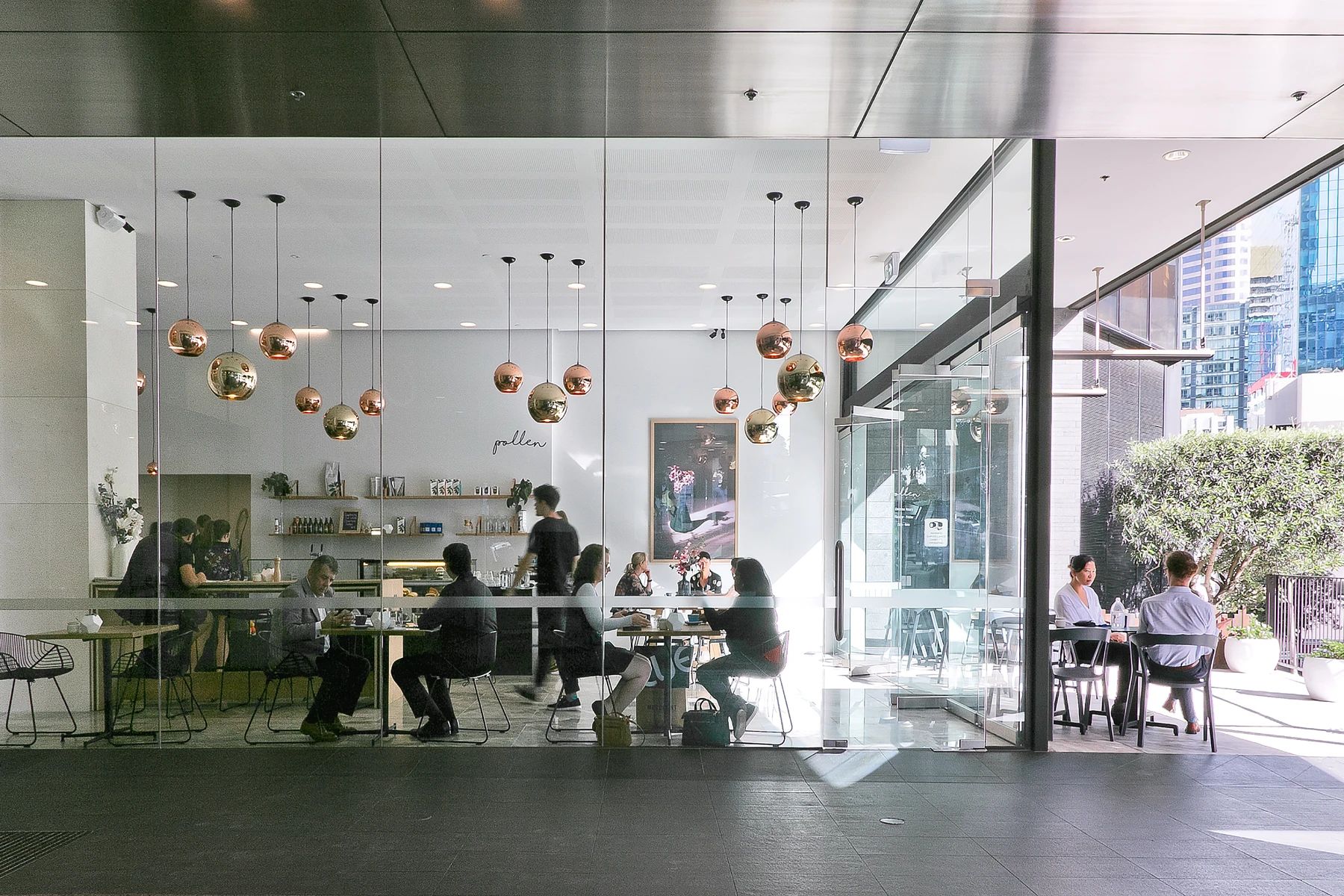 Pollen lobby cafe with clustered copper pendant lights and full-height glazing onto the street